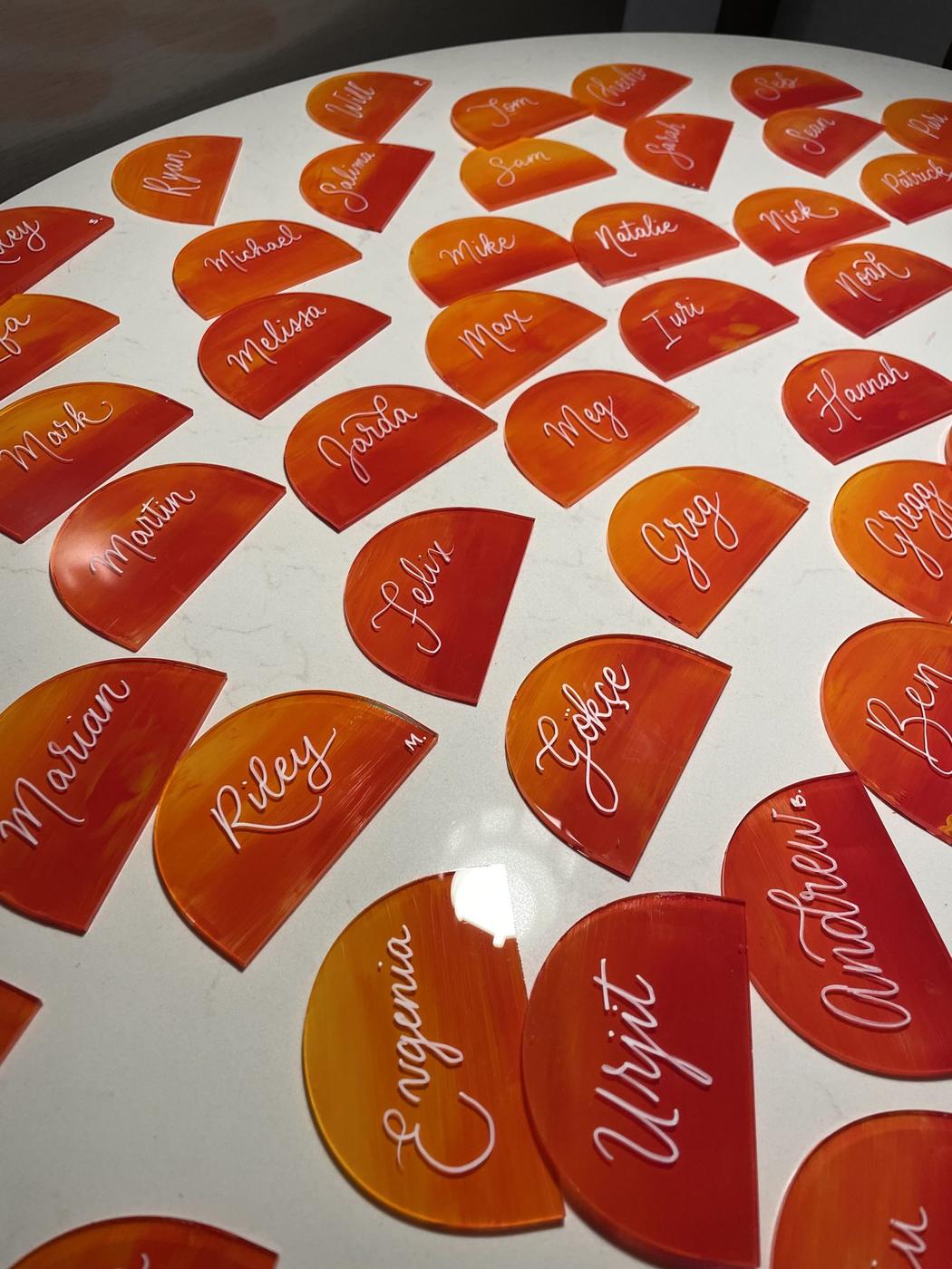 Fan of orange acrylic leaf-shaped place cards with names in white script