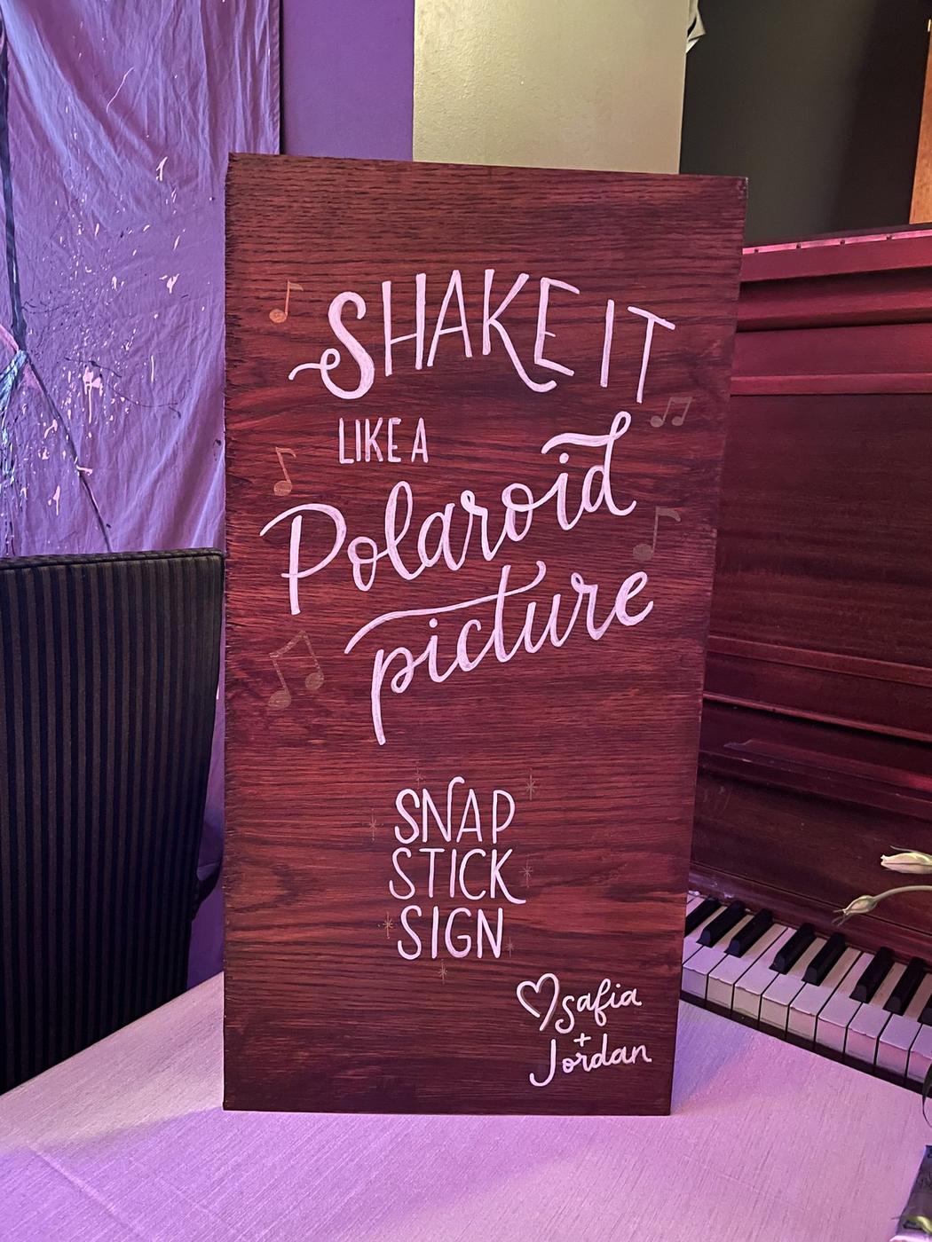 Playful hand-lettered photobooth sign reading Shake It Like a Polaroid Picture